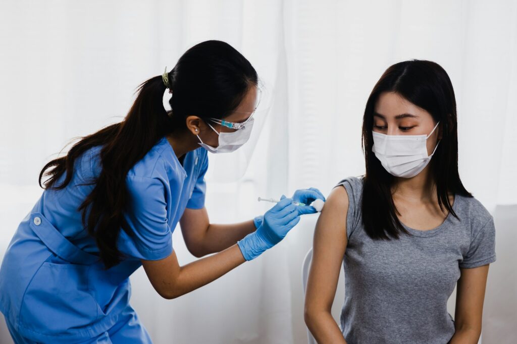 a woman in a mask giving a shot to a woman